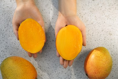 Photo of Woman with halves of ripe mango, top view