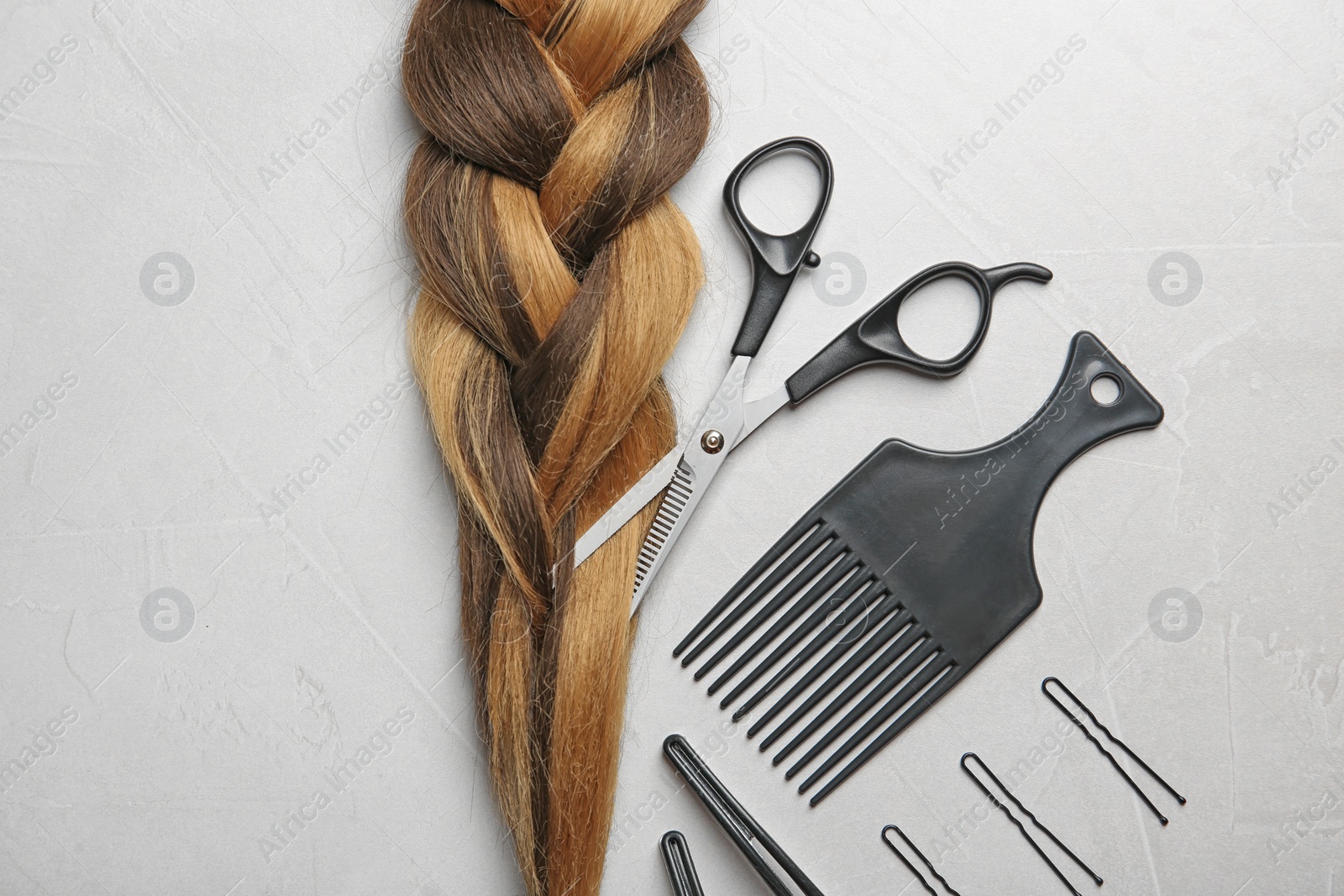 Photo of Flat lay composition with braid and hairdresser's tools on gray background