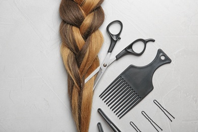 Photo of Flat lay composition with braid and hairdresser's tools on gray background