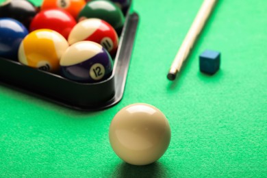 Photo of Billiard balls, triangle rack, chalk and cue on green table