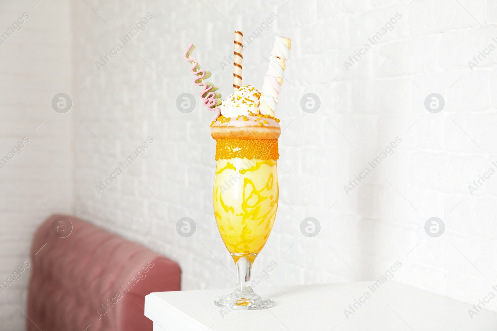 Photo of Glass of tasty milk shake with sweets on table indoors