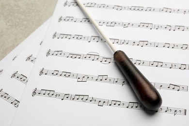 Conductor's baton and sheet music on grey background