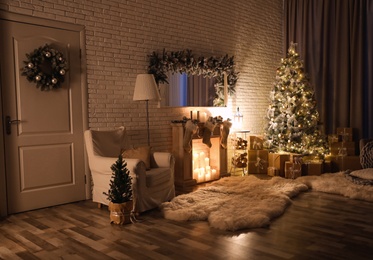 Photo of Stylish interior with beautiful Christmas tree and artificial fireplace at night