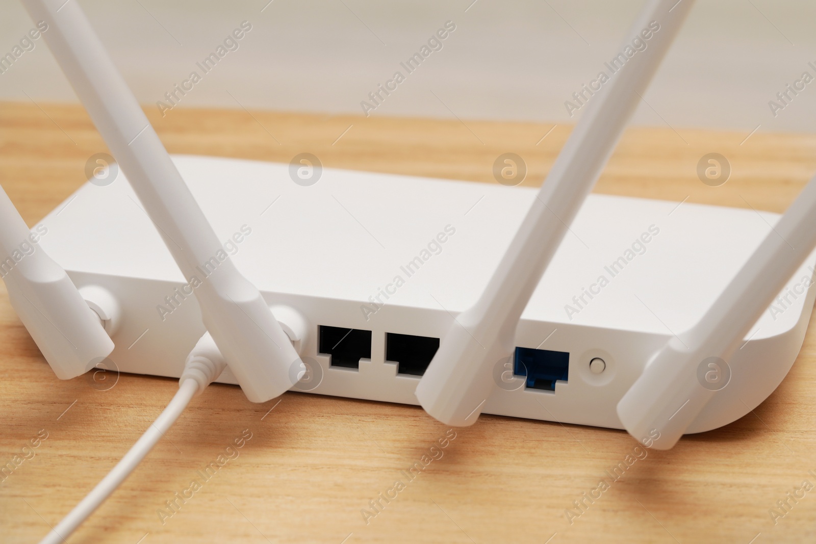 Photo of New white Wi-Fi router on wooden table, closeup