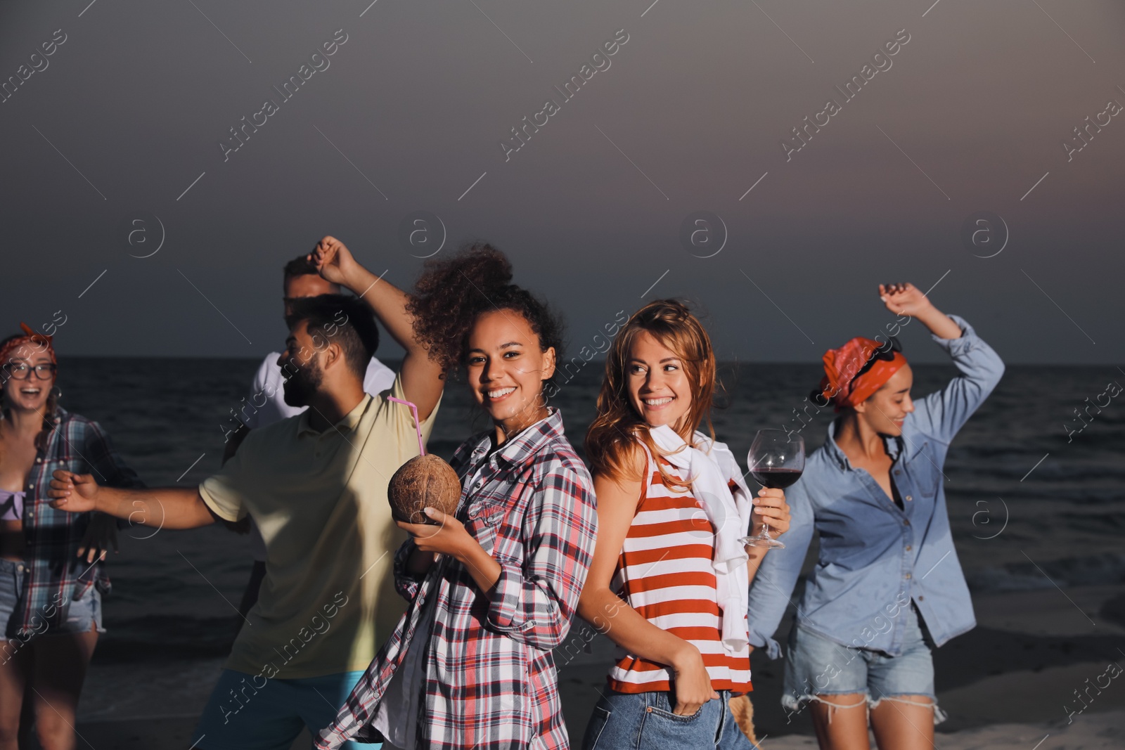 Photo of Happy friends enjoying summer beach party in evening