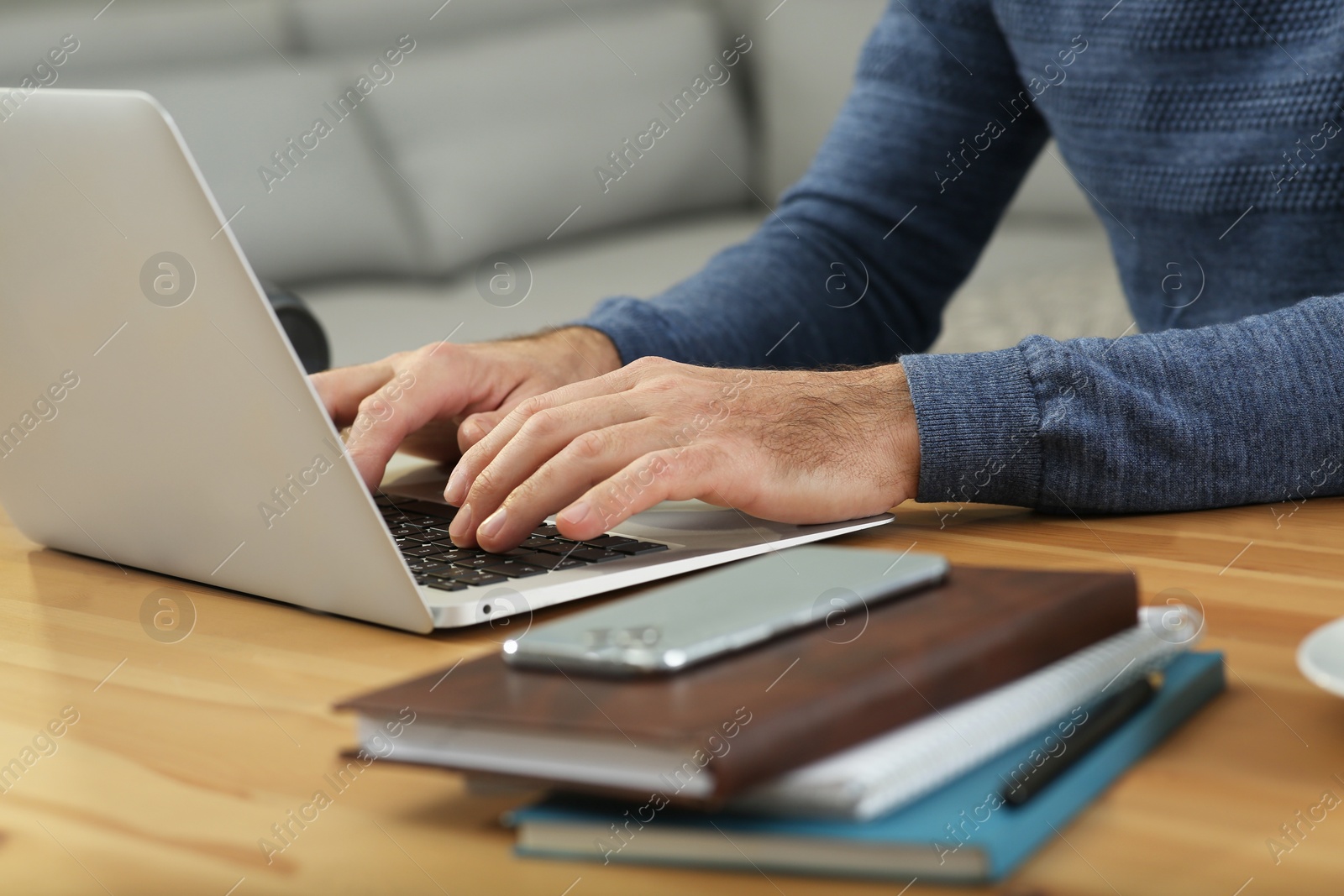 Photo of Man with laptop learning at wooden table indoors, closeup