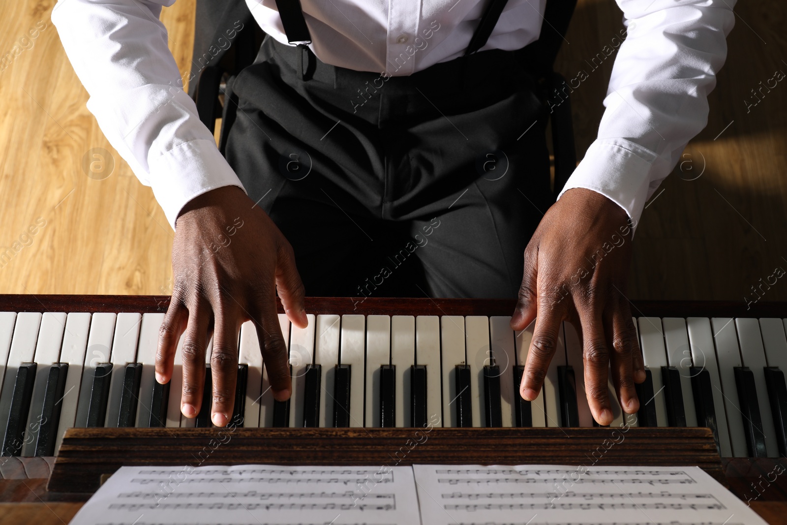 Photo of African-American man playing piano indoors, above view. Talented musician