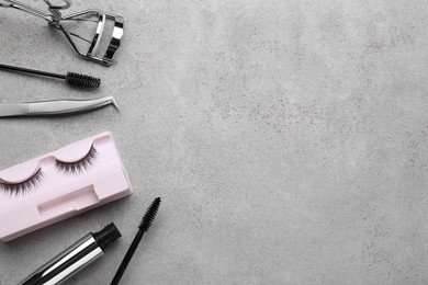Photo of Flat lay composition with false eyelashes and tools on light grey background. Space for text