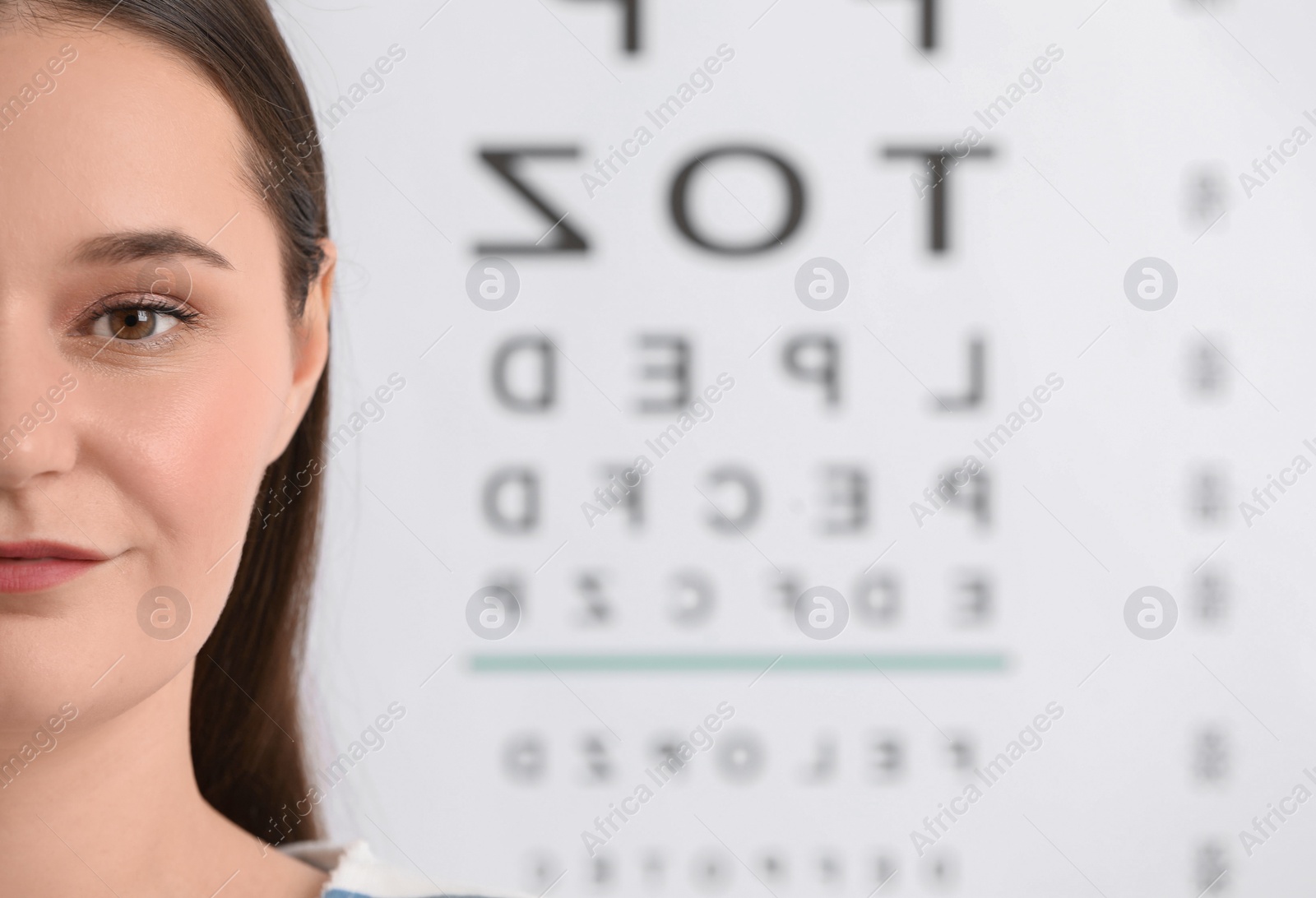 Photo of Young woman against vision test chart, closeup