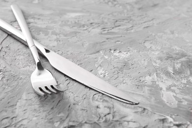 Stylish cutlery. Silver knife and fork on grey textured table, closeup