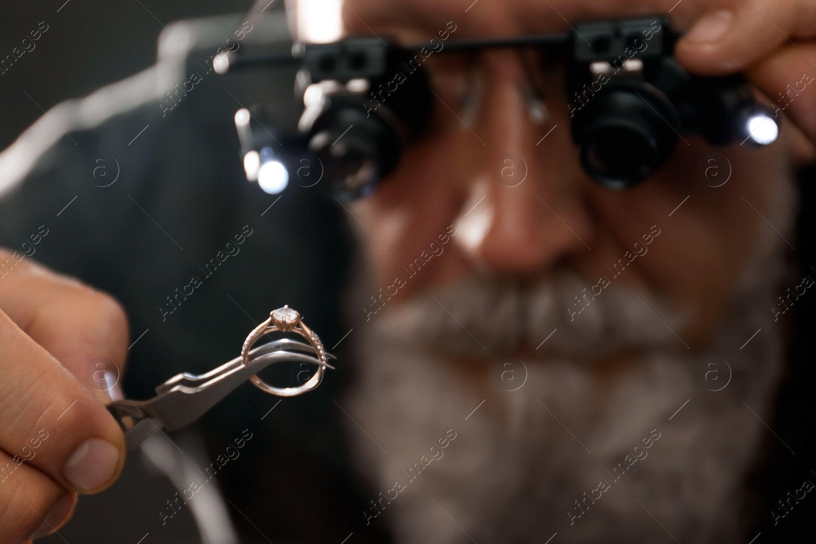 Photo of Male jeweler evaluating diamond ring in workshop, closeup view