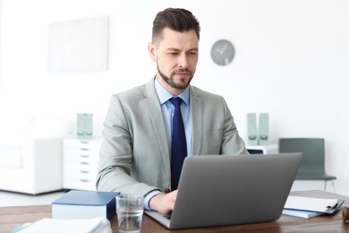 Photo of Male lawyer working with laptop in office