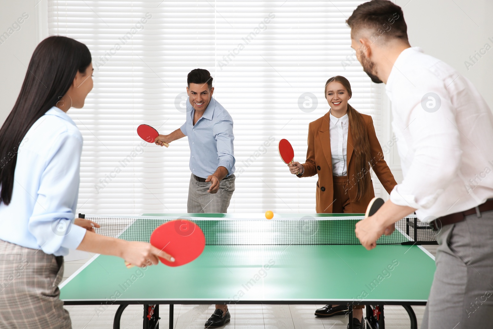 Photo of Business people playing ping pong in office