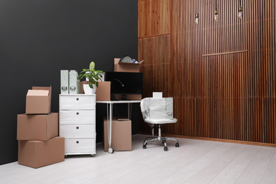 Photo of Cardboard boxes and packed belongings in office. Moving day