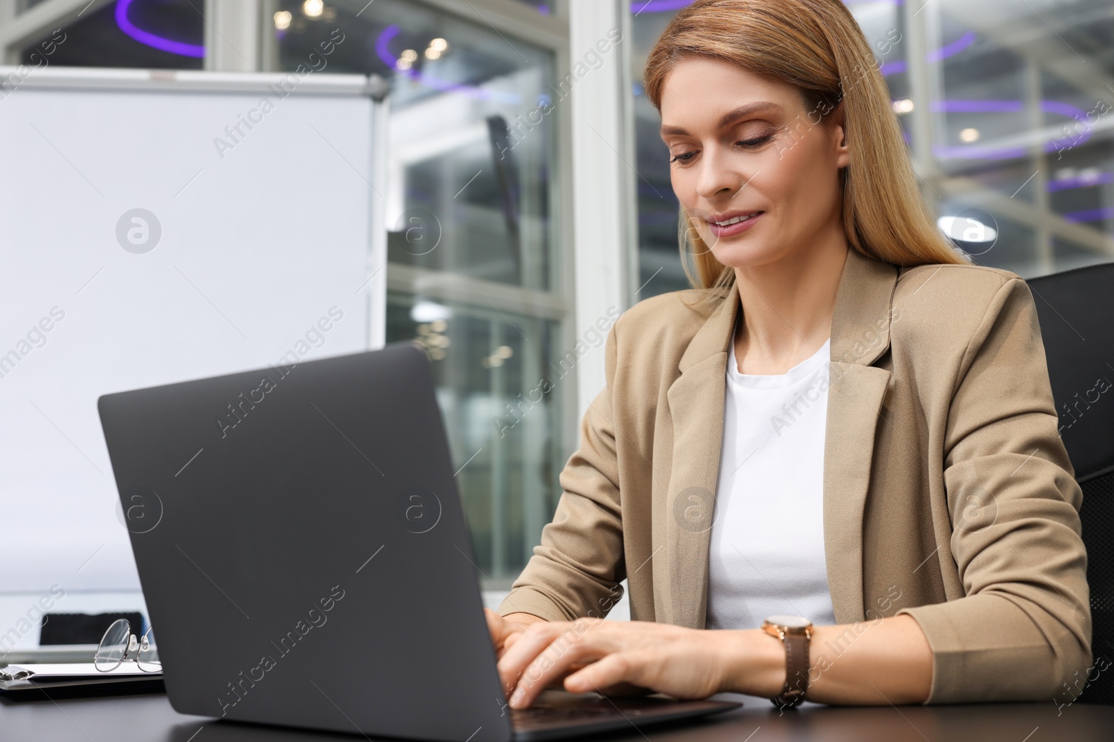 Photo of Woman working on laptop at black desk in office