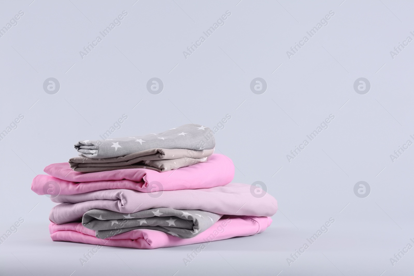 Photo of Stack of clean bed sheets on white background. Space for text