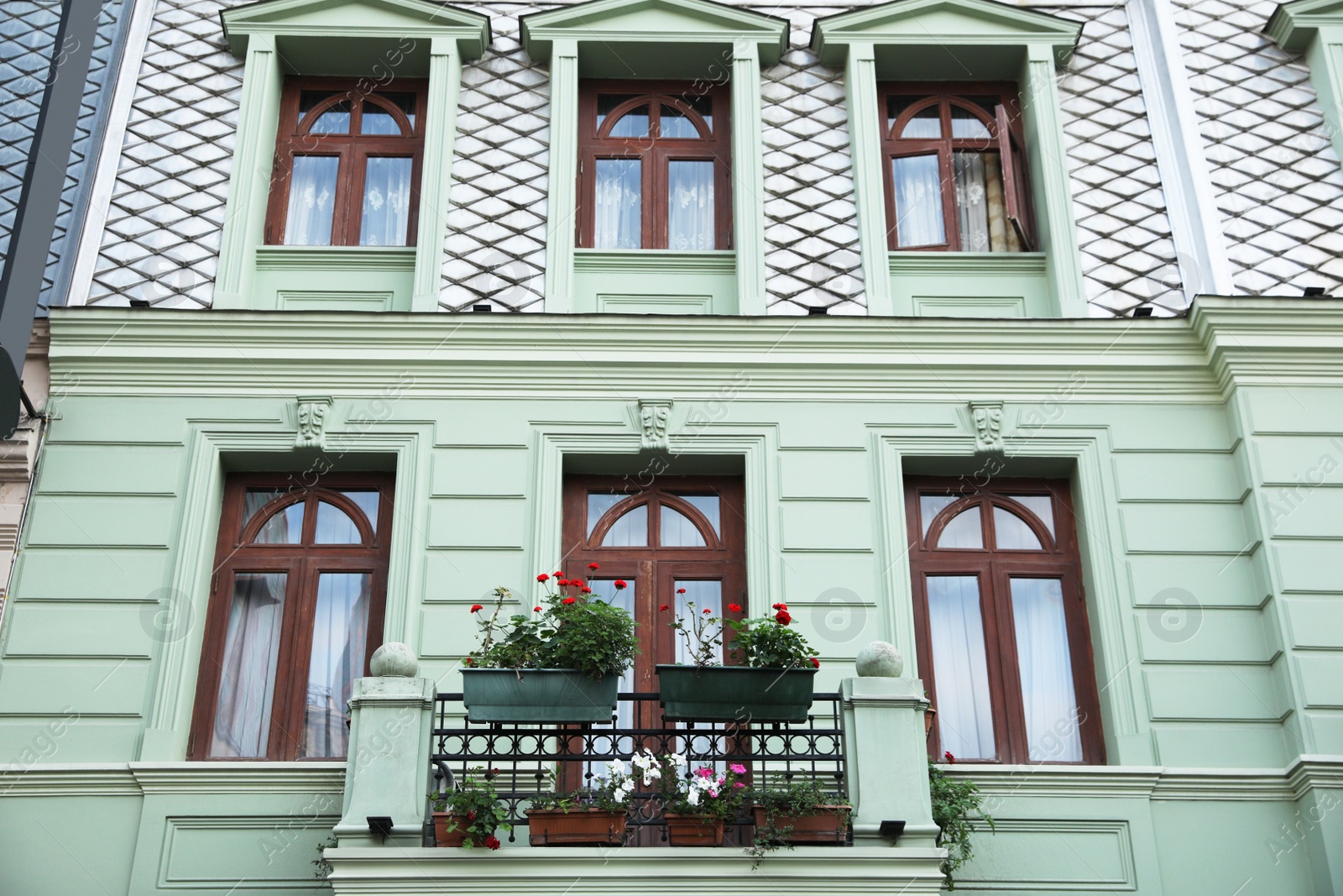 Photo of Exterior of beautiful residential building with flowers on balcony, low angle view