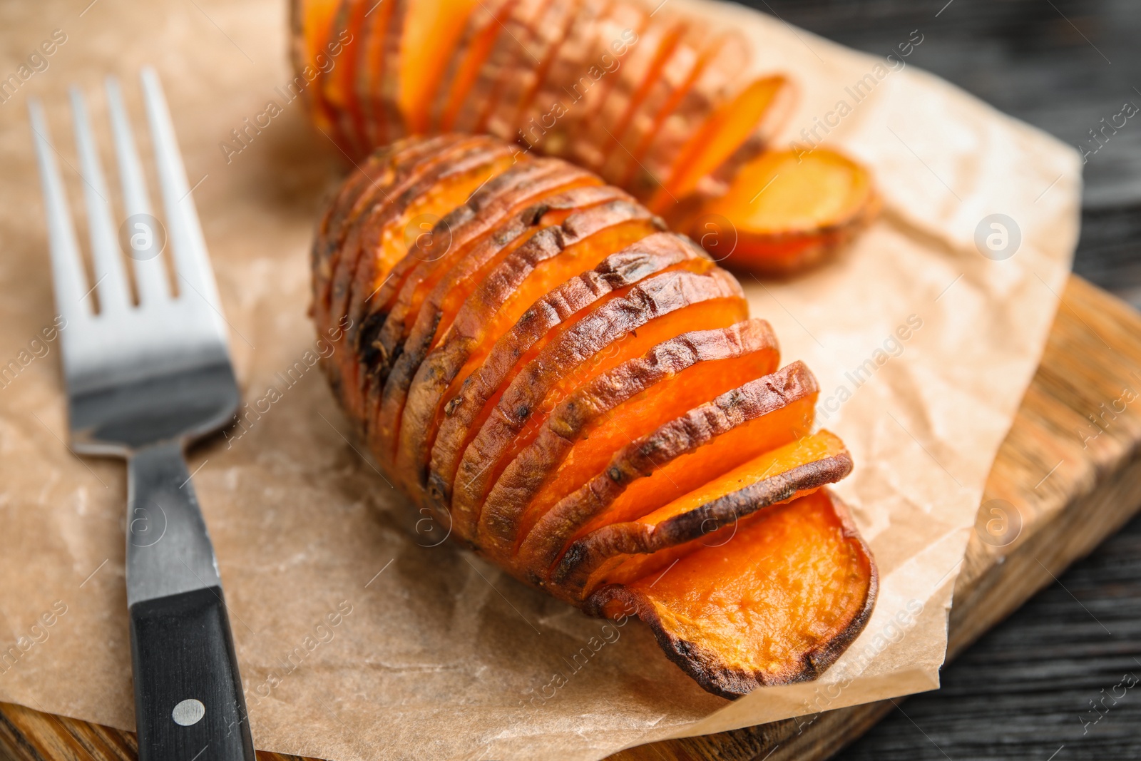 Photo of Delicious baked sweet potatoes on parchment, closeup