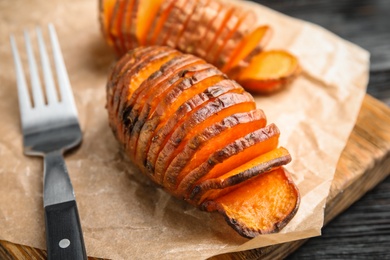 Photo of Delicious baked sweet potatoes on parchment, closeup