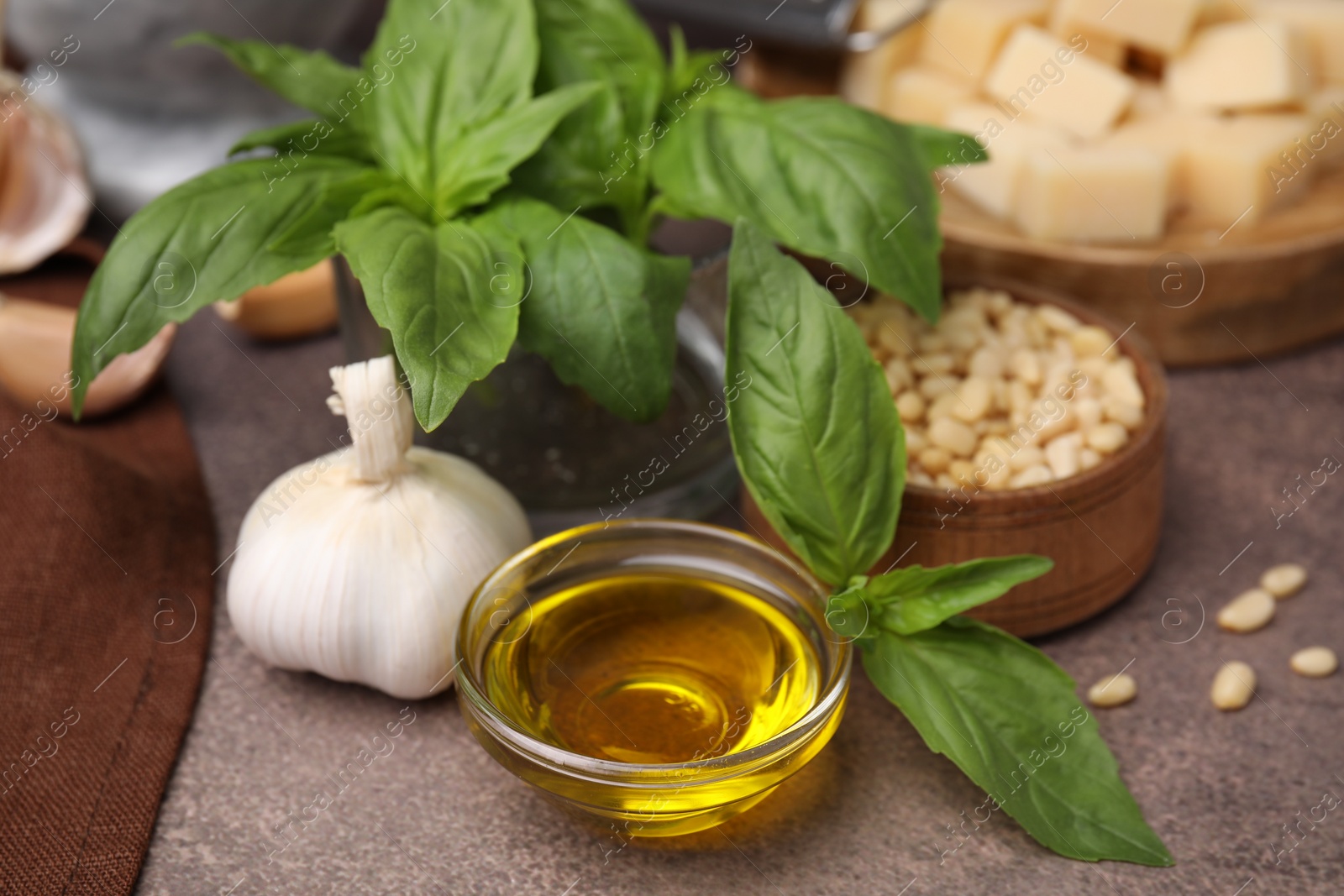 Photo of Different ingredients for cooking tasty pesto sauce on brown textured table, closeup