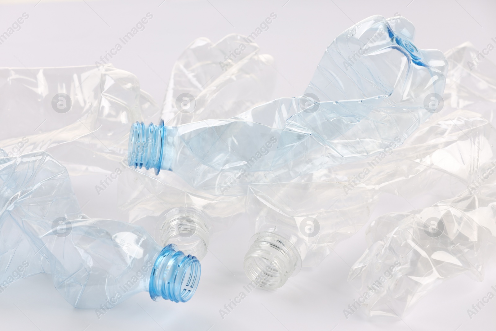 Photo of Crumpled disposable plastic bottles on white background