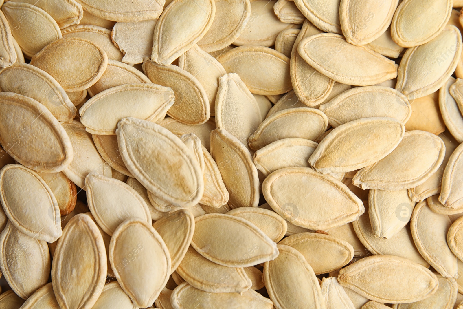 Photo of Raw unpeeled pumpkin seeds as background, top view