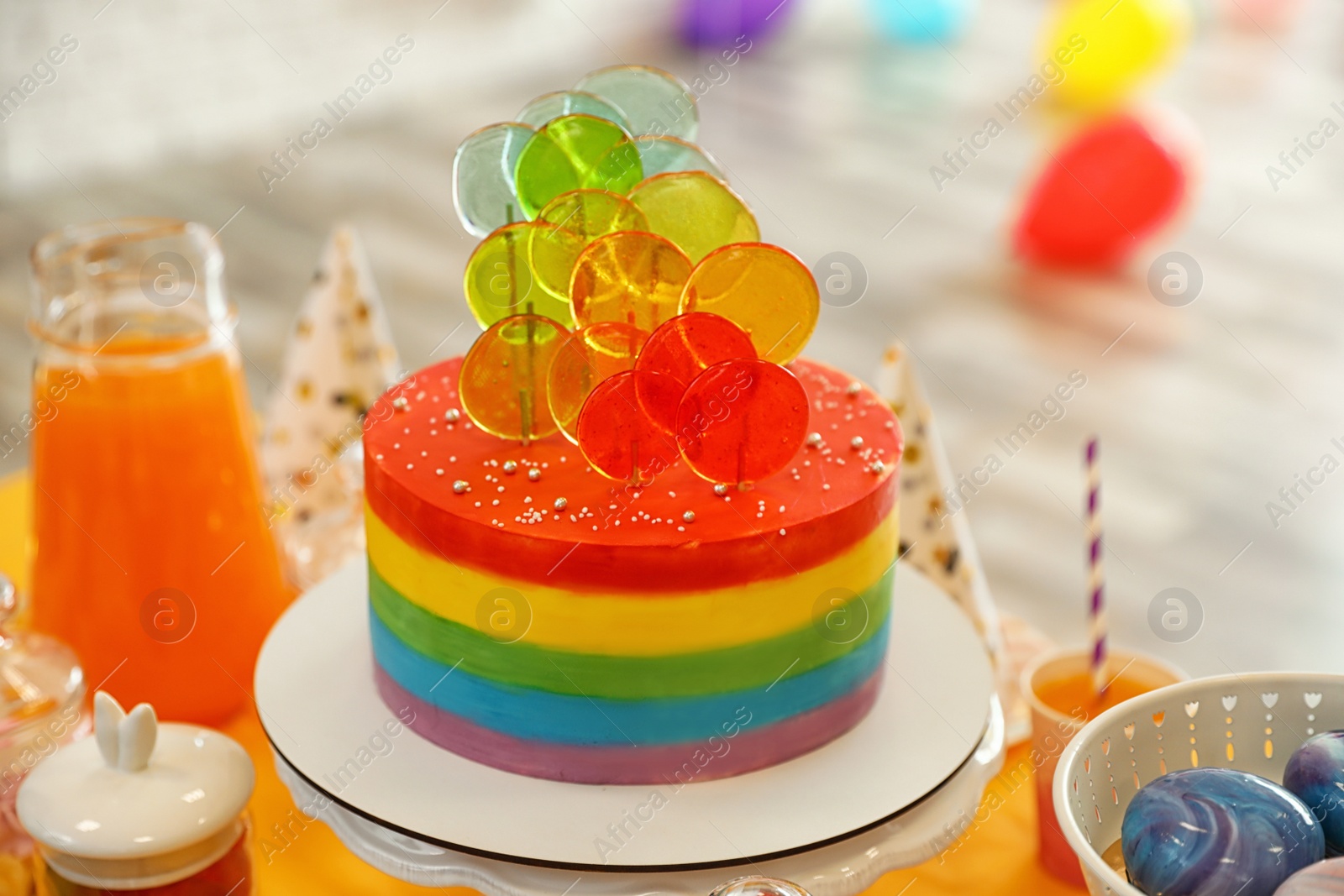 Photo of Bright birthday cake and other treats on table in decorated room