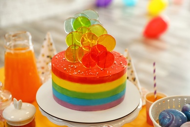 Photo of Bright birthday cake and other treats on table in decorated room