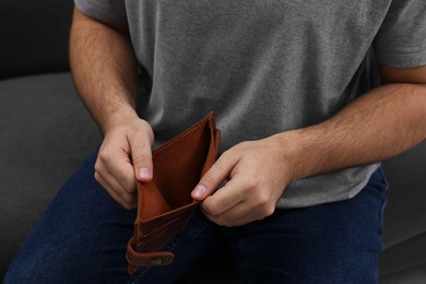 Man with empty wallet on sofa, closeup