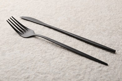 Photo of Stylish cutlery on beige textured table, closeup