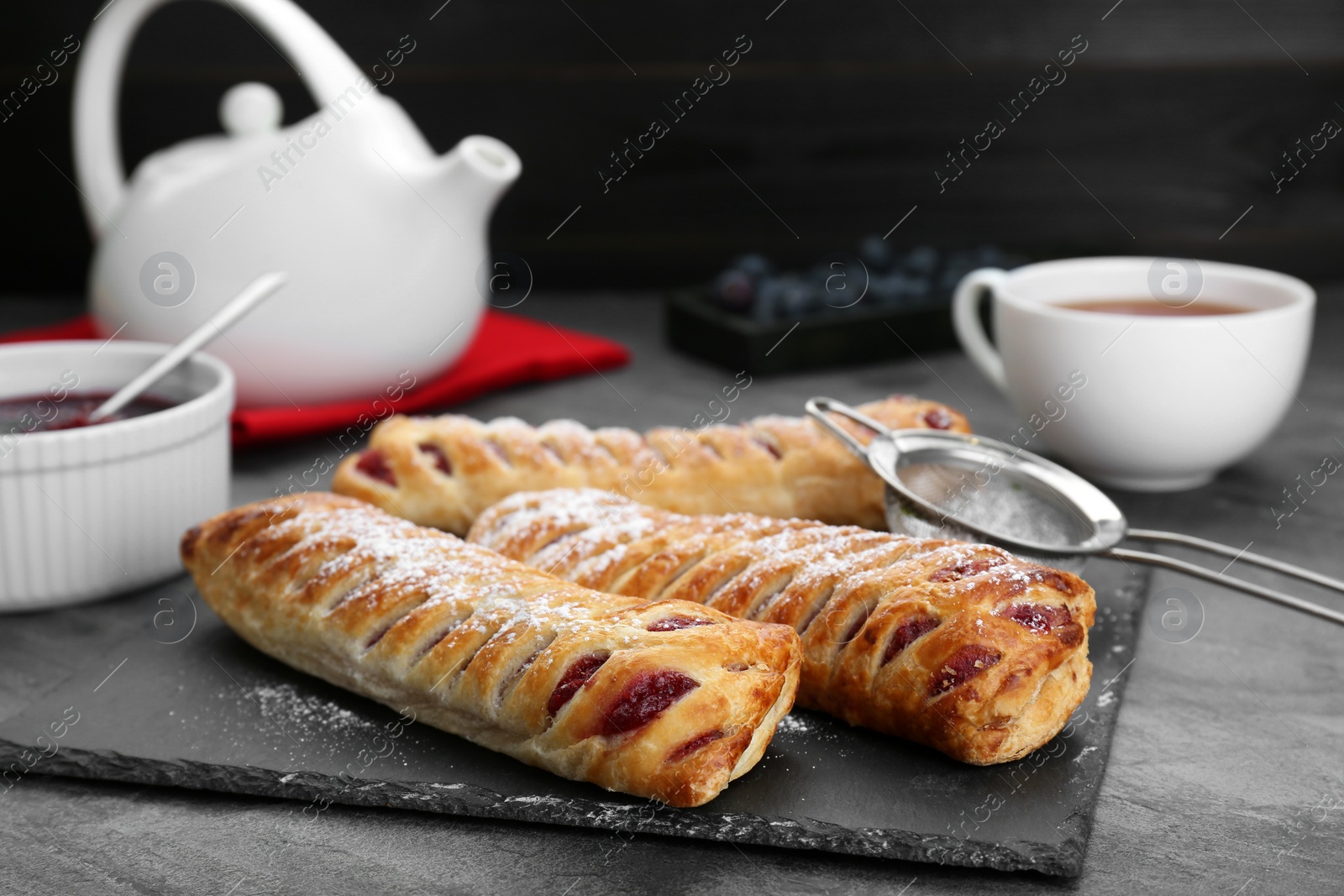 Photo of Fresh tasty puff pastry with sugar powder on grey table, closeup