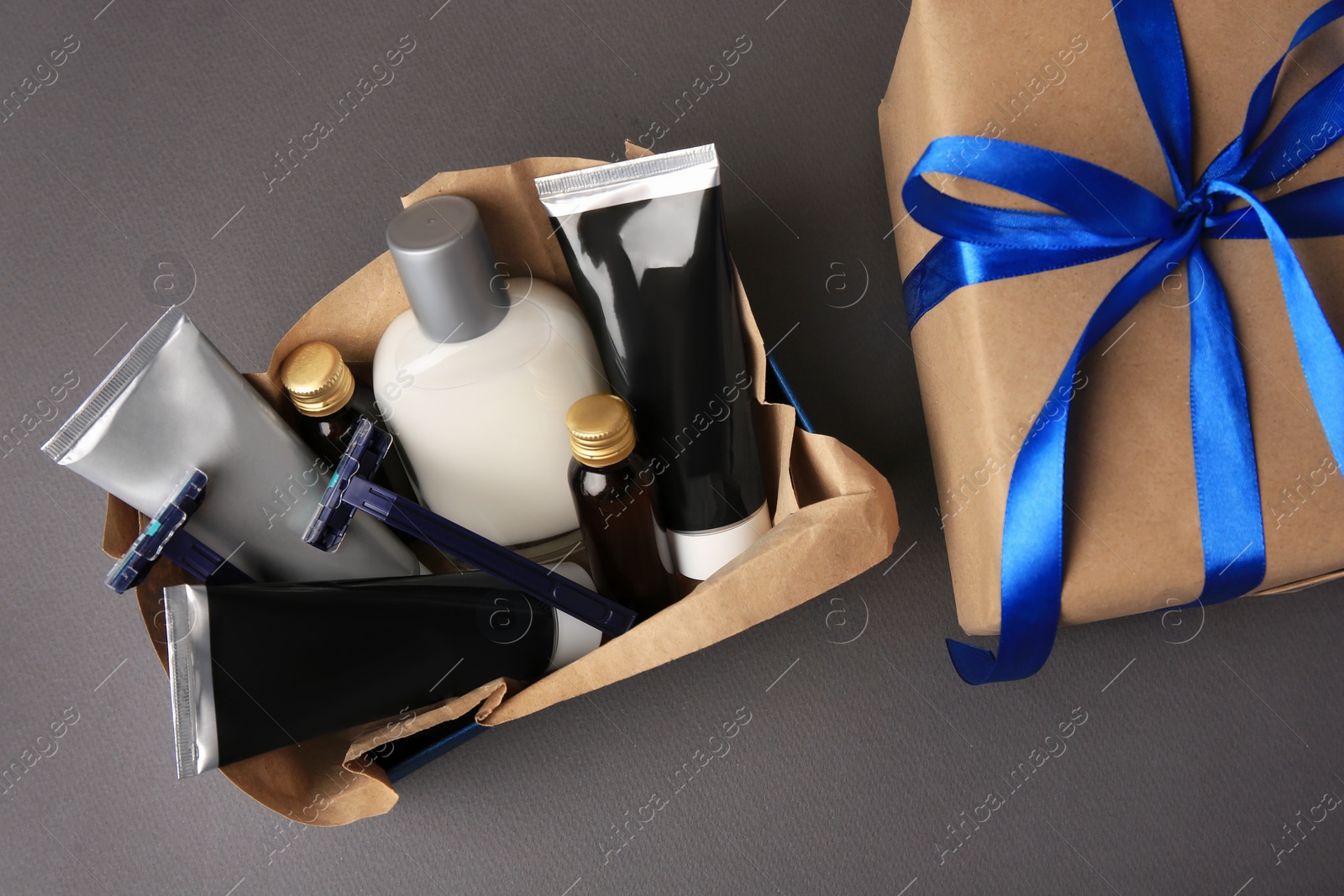 Photo of Gift box with different men's shaving accessories and cosmetics on dark grey background, flat lay