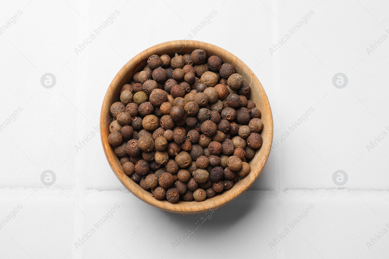 Photo of Dry allspice berries (Jamaica pepper) on white tiled table, top view