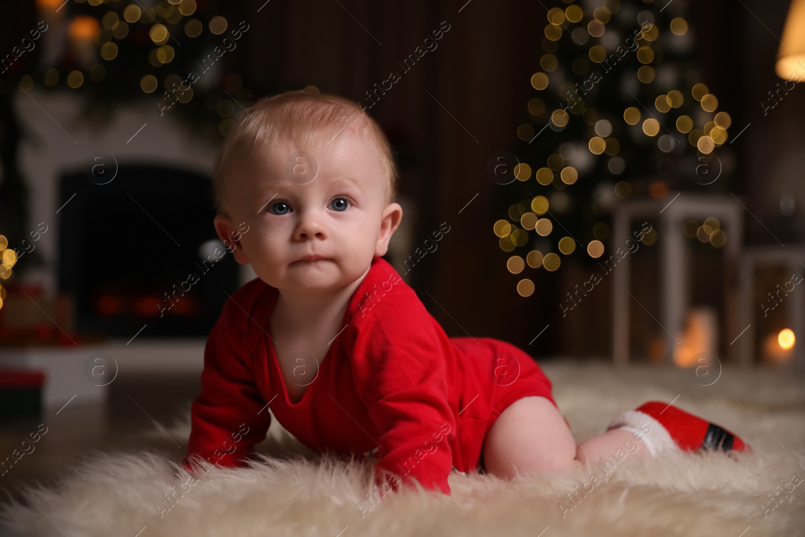 Photo of Cute little baby wearing red bodysuit on floor at home. Christmas celebration