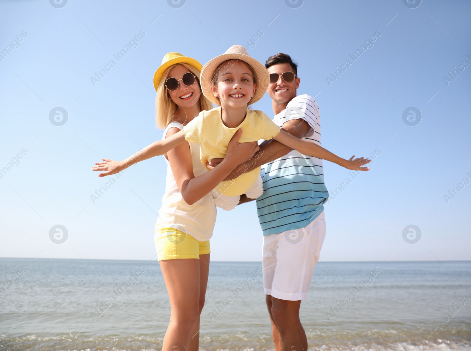 Photo of Parents playing with daughter at beach. Family vacation