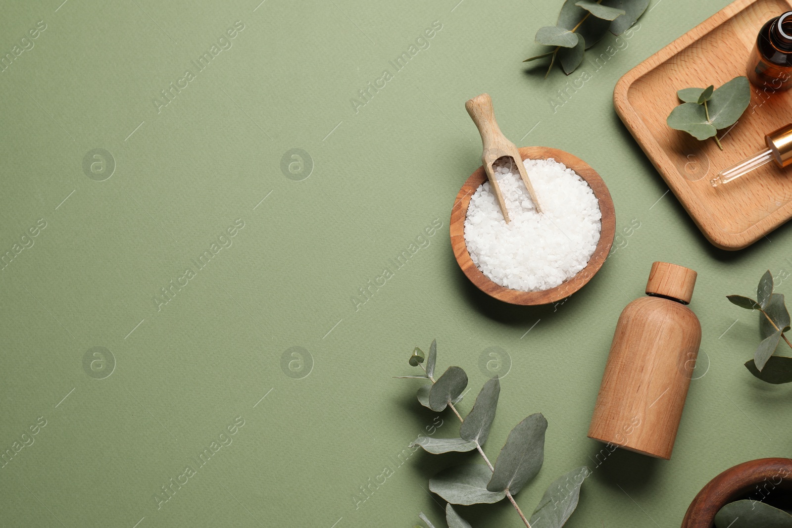 Photo of Aromatherapy products. Bottles of essential oil, sea salt and eucalyptus leaves on olive background, flat lay. Space for text