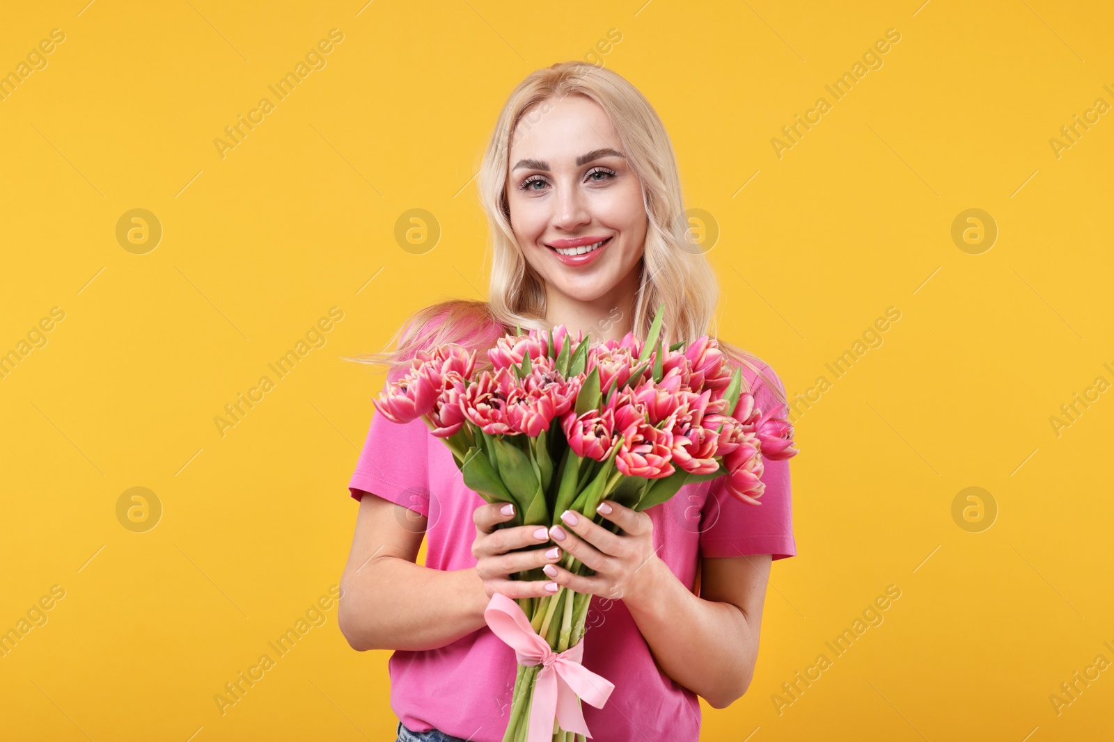 Photo of Happy young woman with beautiful bouquet on orange background