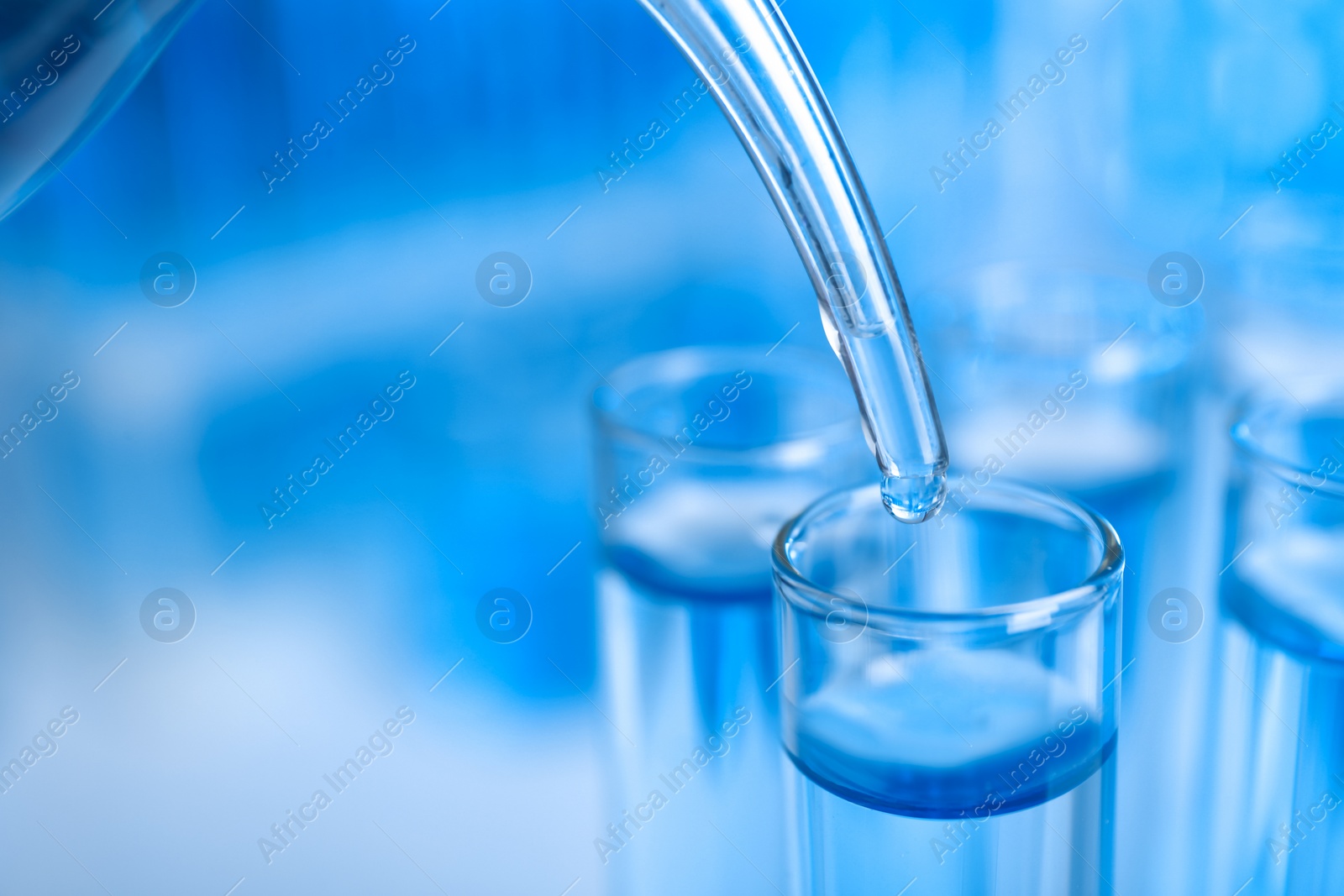 Photo of Dripping reagent into test tube with liquid sample on blurred background, closeup. Laboratory analysis