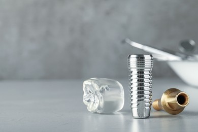 Photo of Parts of dental implant on grey table. Space for text