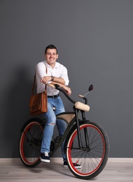 Photo of Portrait of handsome young man with bicycle near color wall