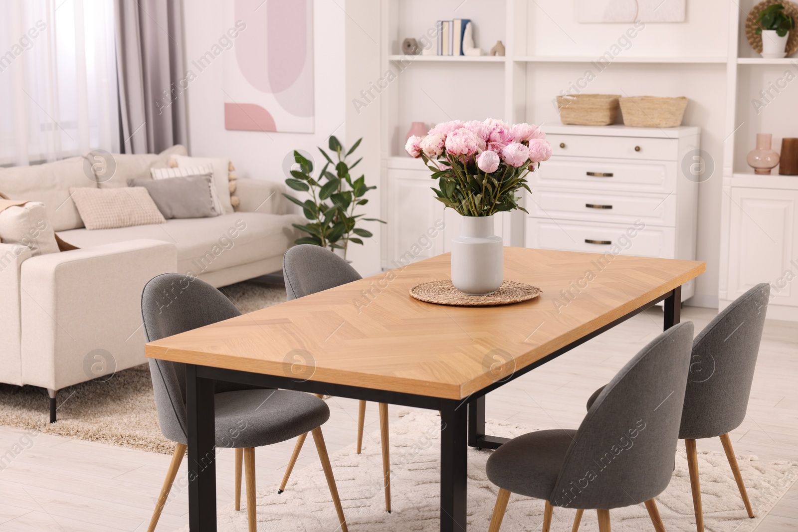 Photo of Stylish dining room with cosy furniture and flowers