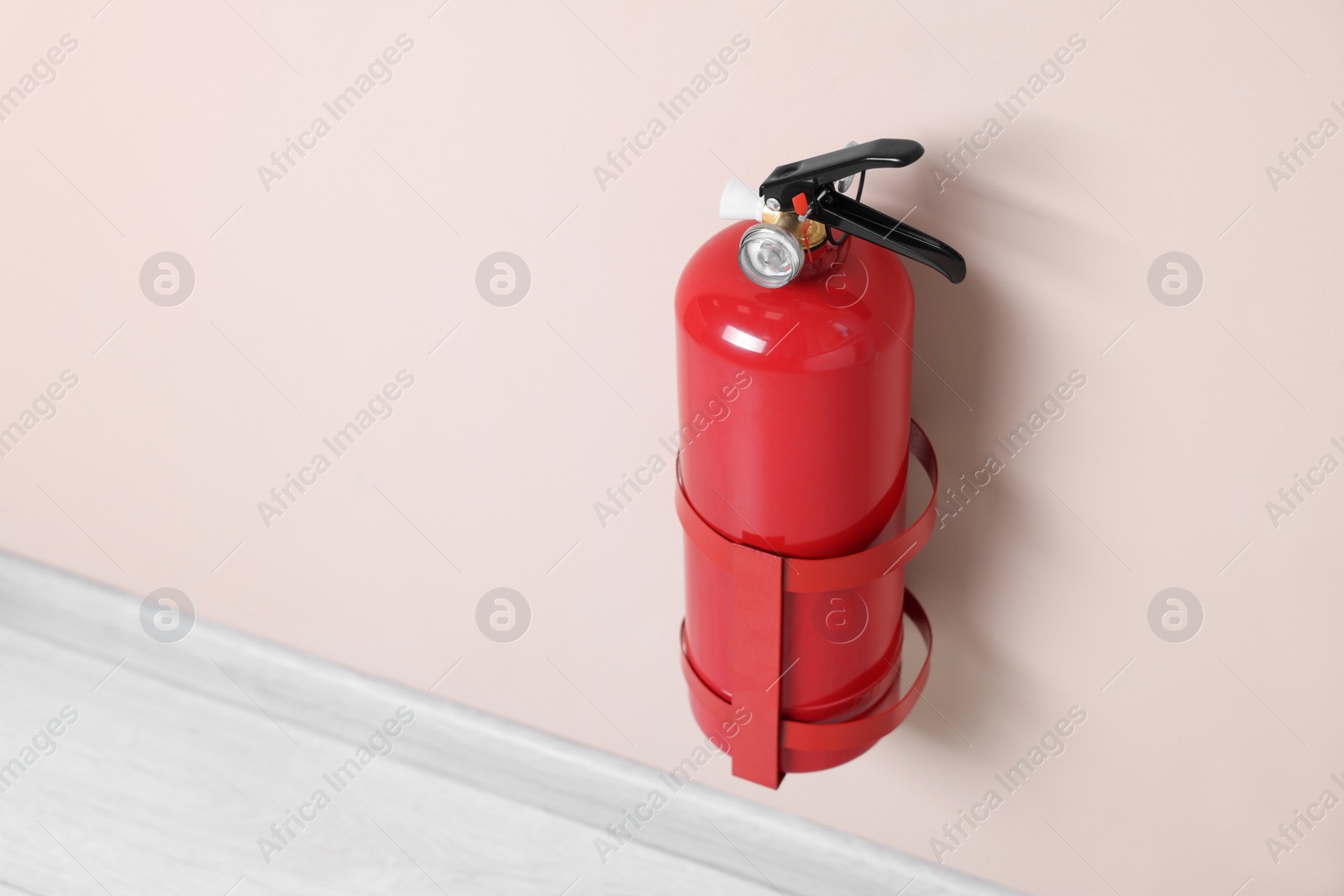 Photo of One fire extinguisher on beige wall, space for text