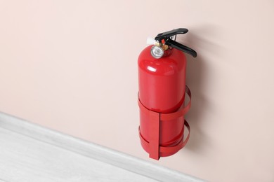 One fire extinguisher on beige wall, space for text
