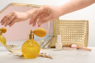 Photo of Woman taking crystal bottle of luxurious perfume from dressing table, closeup. Space for text