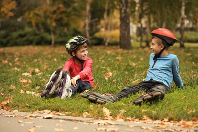 Photo of Cute roller skaters sitting on grass in park
