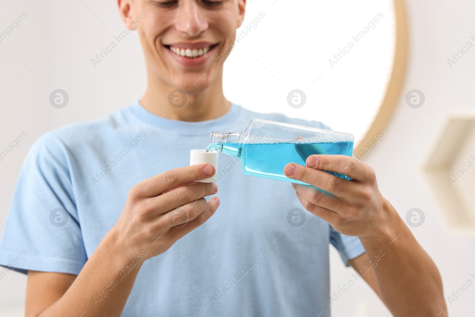 Photo of Young man using mouthwash in bathroom, closeup