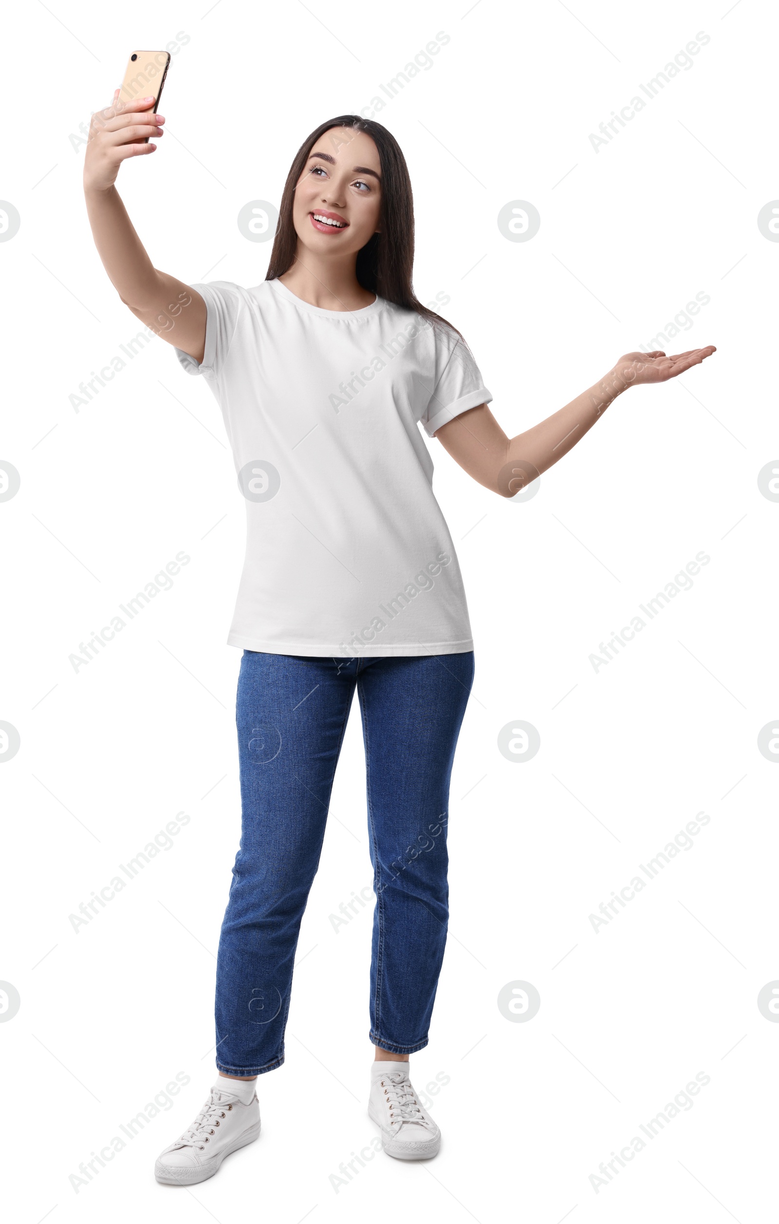 Photo of Smiling young woman taking selfie with smartphone on white background