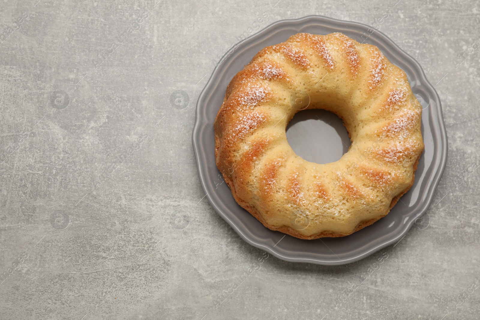 Photo of Delicious freshly baked sponge cake on gray table, top view. Space for text