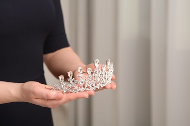 Photo of Woman holding luxurious tiara indoors, closeup. Space for text