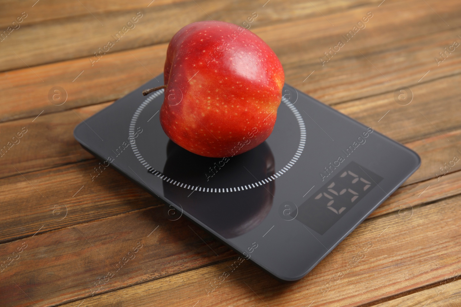 Photo of Ripe red apple and electronic scales on wooden table